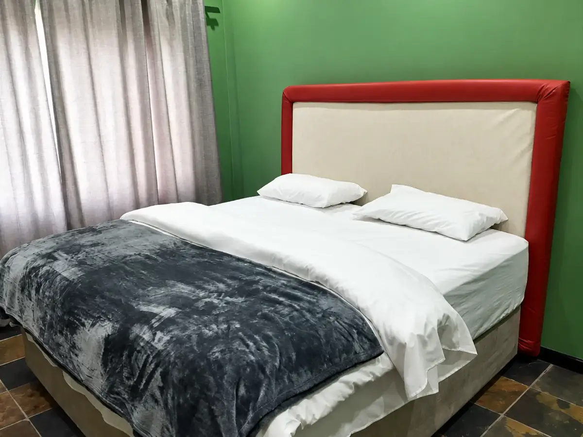 Guest room with green wall and grey throw